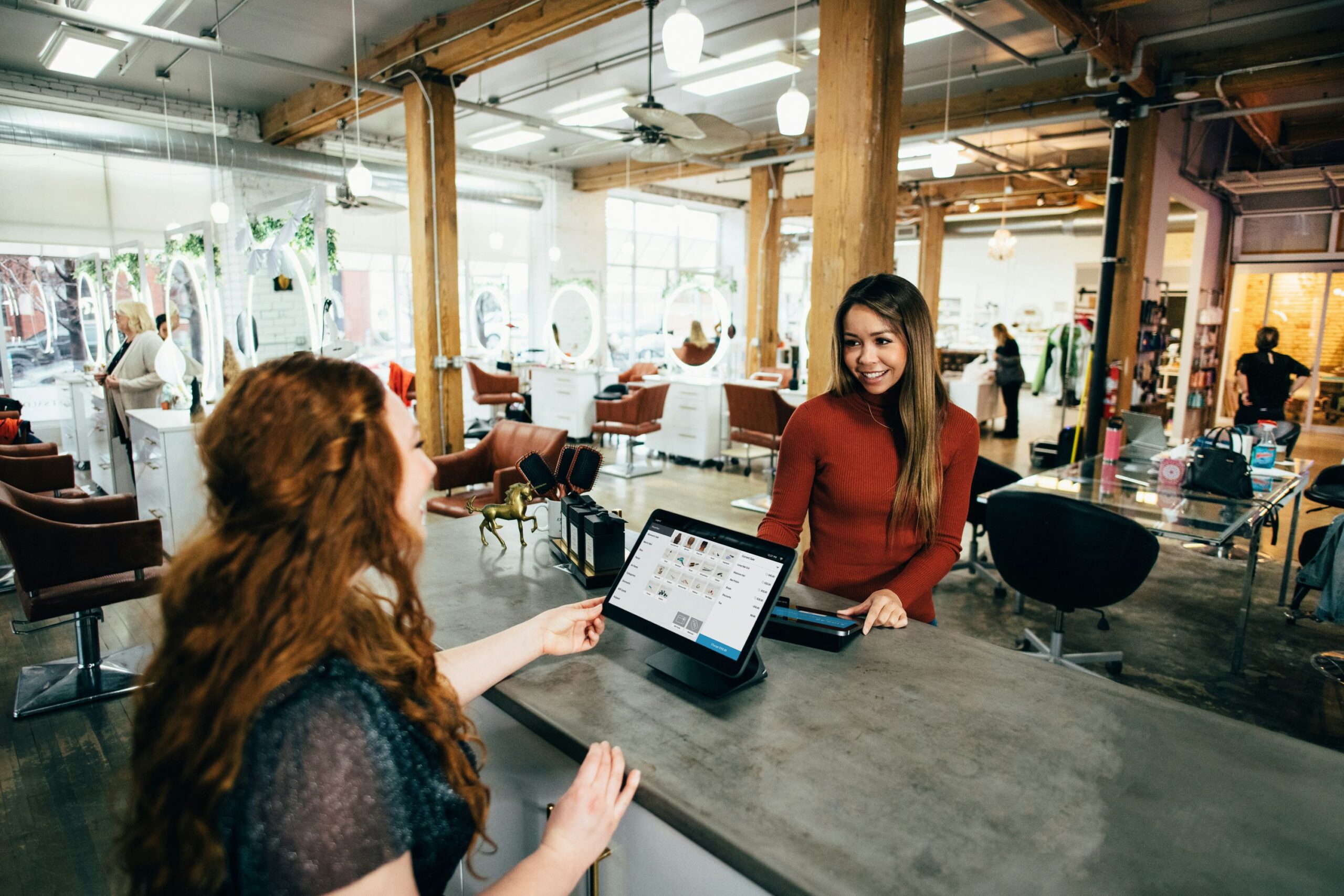 two people sat in an office smiling using a laptop